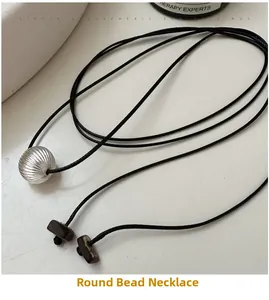 Detail view of S925 silver textured bead pendant on a minimalist black rope necklace