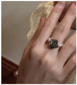 Macro detail of gothic black rose ring with silver beaded band on a finger