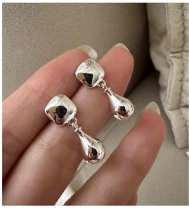 Macro shot of silver teardrop earrings with a polished mirror finish and geometric design