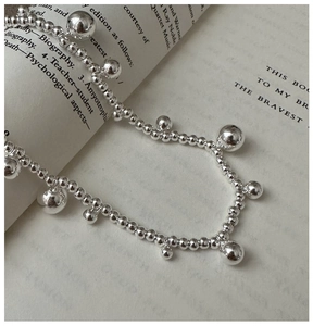 Detail of S925 sterling silver beaded necklace with large metallic sphere on book pages