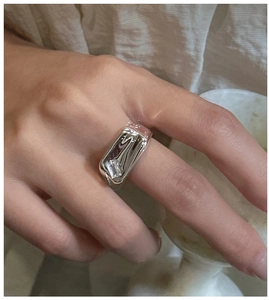 Detail of liquid metal style silver ring with square zircon on index finger