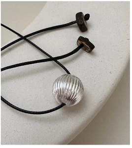 Macro detail of S925 silver textured sphere pendant on a black cord necklace