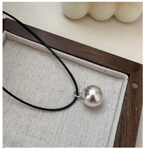 Close-up of a S925 sterling silver ball pendant on a minimalist black cord necklace