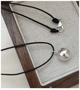 Macro shot of 925 sterling silver ball pendant and lobster clasp on black cord necklace