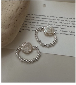 Detailed shot of beaded silver ring with white rose charm on a minimalist background