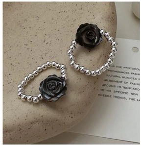 Detail of S925 silver beaded rings featuring a black resin rose on a stone tray