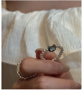 Detailed view of an elastic silver beaded ring featuring a black shell cat head charm