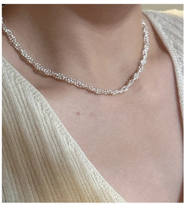 Gros plan du collier triple rang en argent S925 avec texture de chaîne torsadée scintillante