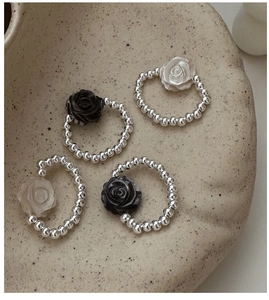 Detail view of four S925 silver beaded rings with black and white rose charms on a tray