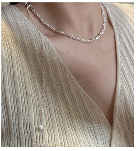 Gros plan d'un collier superposé en argent S925 montrant les détails de la chaîne torsadée