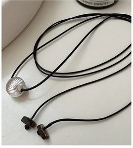 Detailed close-up of textured silver bead pendant on a black cord necklace