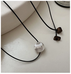 Close-up of S925 silver textured bead pendant with black cord and wooden beads