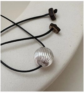 Detailed macro view of a silver textured bead pendant on an adjustable black cord necklace