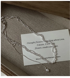 Gros plan du collier triple rang en argent sterling avec chaînes torsadées et fines perles