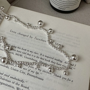 Minimalist S925 sterling silver beaded necklace displayed on a vintage book page
