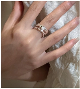 Close-up of a silver crossover ring featuring a hammered texture on a model hand
