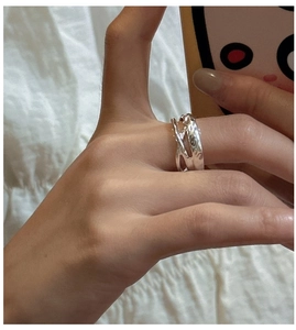 Close-up of minimalist S925 sterling silver ring with textured crossover layered design