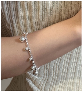 Detail of S925 sterling silver beaded bracelet with dangling charms on female wrist