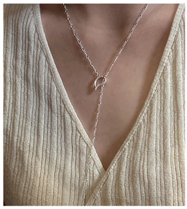 Detail of silver S925 Figaro OT necklace with teardrop toggle on a knit sweater