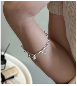 Detail of S925 sterling silver laser beaded bracelet with dangling charms on a wrist