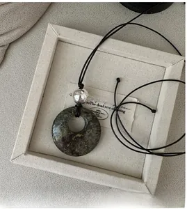 Détail d'un long collier en argent S925 avec pendentif rond en pierre naturelle verte