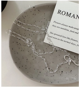Detail of S925 sterling silver Figaro chain with heart-shaped toggle clasp on ceramic tray