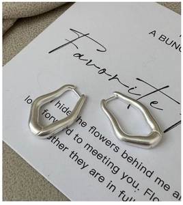 Detail of matte silver irregular geometric earrings on a minimalist display card