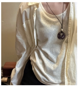 Close-up of a purple agate donut pendant necklace worn with a minimalist linen shirt