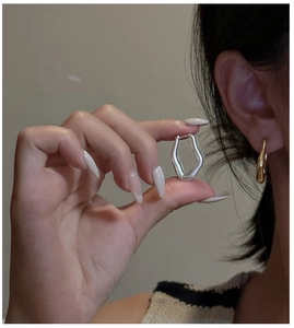 Macro shot of irregular geometric hoop earrings in polished silver and gold finish