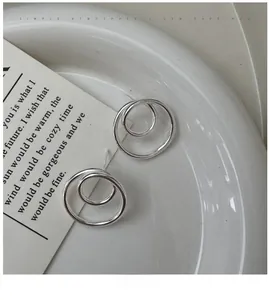 Detailed macro view of S925 sterling silver interlocking double hoop earrings on white plate