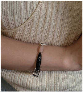 Dettaglio del bracciale di perle con agata nera e pietra rosa sul polso donna
