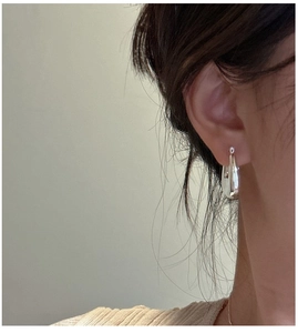 Close-up of minimalist silver teardrop earrings worn by a model in a modern style