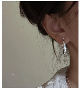 Close-up of minimalist sterling silver chunky hoop earring on model ear showing glossy finish