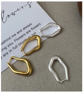 Close-up of matte geometric S925 silver earrings in gold and silver finishes on art card