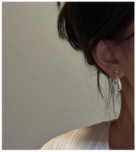 Close-up of minimalist silver 925 C-shaped square hoop earrings on a female model
