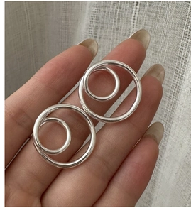 Detail of silver S925 minimalist double hoop earrings held to show scale and texture