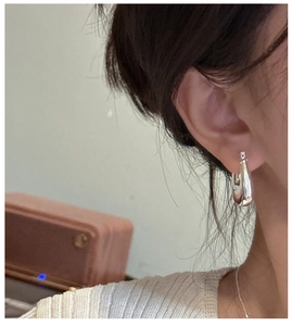 Macro detail of polished 925 sterling silver square hoop earrings on a model