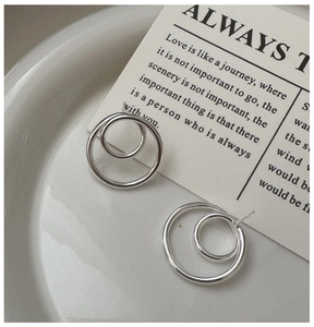Macro detail of minimalist S925 silver interlocking hoop earrings on a ceramic dish