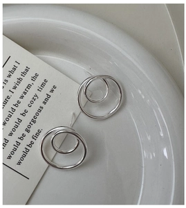 Detail of S925 sterling silver double hoop earrings on a white ceramic display tray