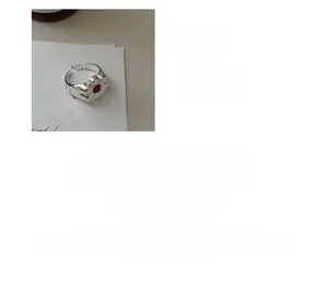 Macro shot of S925 sterling silver ring with hollow flower design and red gemstone