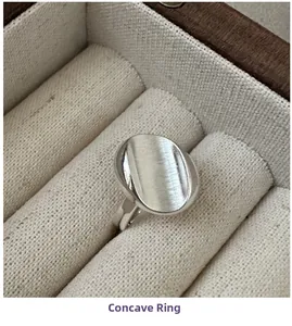 Macro shot of minimalist silver concave ring with brushed metal texture in a wooden box