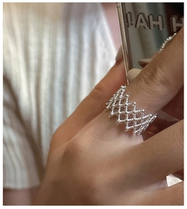 Close-up of a silver mesh hollow ring with a minimalist woven geometric design on a finger