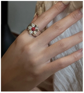 Close-up of S925 silver flower ring featuring a red gemstone on model's finger