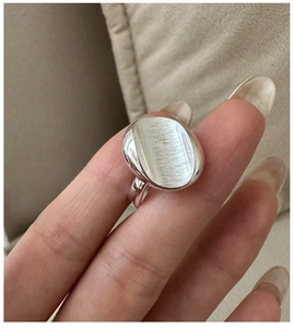 Close-up of minimalist S925 sterling silver ring featuring a brushed oval surface on finger