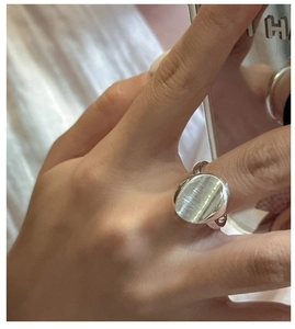 Close-up of minimalist S925 sterling silver ring with brushed oval surface on finger