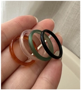 Gros plan de quatre bagues minimalistes en agate en ambre, rose, vert et noir