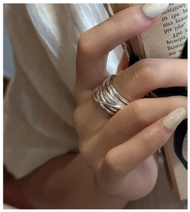 Detail of S925 sterling silver multilayer crossover ring worn on finger over vintage book
