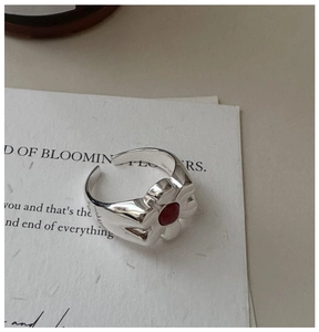Macro shot of silver ring with red gemstone and fine engraved logo on the band