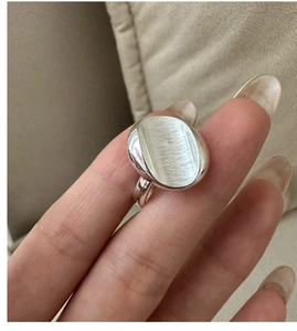 Macro detail of minimalist silver ring showing brushed oval surface and polished edges