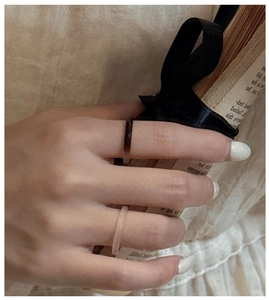 Gros plan de bagues fines en agate sur main avec styles rose mat et facettes foncées